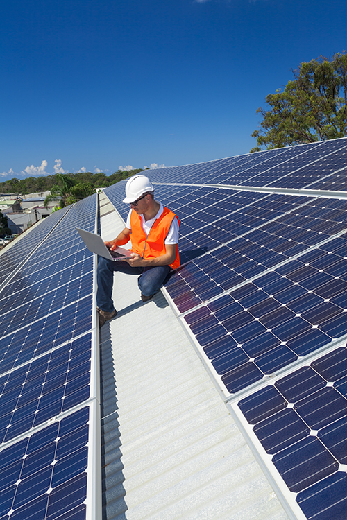 A technician checking solar panels on factory roof