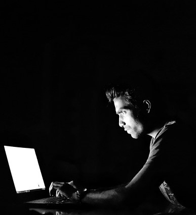 decorative black-and-white image of a man in front of a laptop