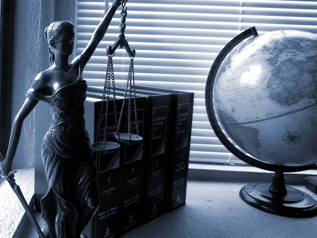 decorative image of an office desk with books, a globe and a miniature figure of Lady Justice